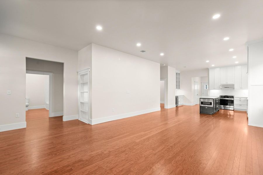 A sleek, open-concept living area seamlessly transitions into a modern kitchen, featuring warm hardwood flooring throughout. A sleek, open-concept living area seamlessly transitions into a modern kitchen, featuring warm hardwood flooring throughout.