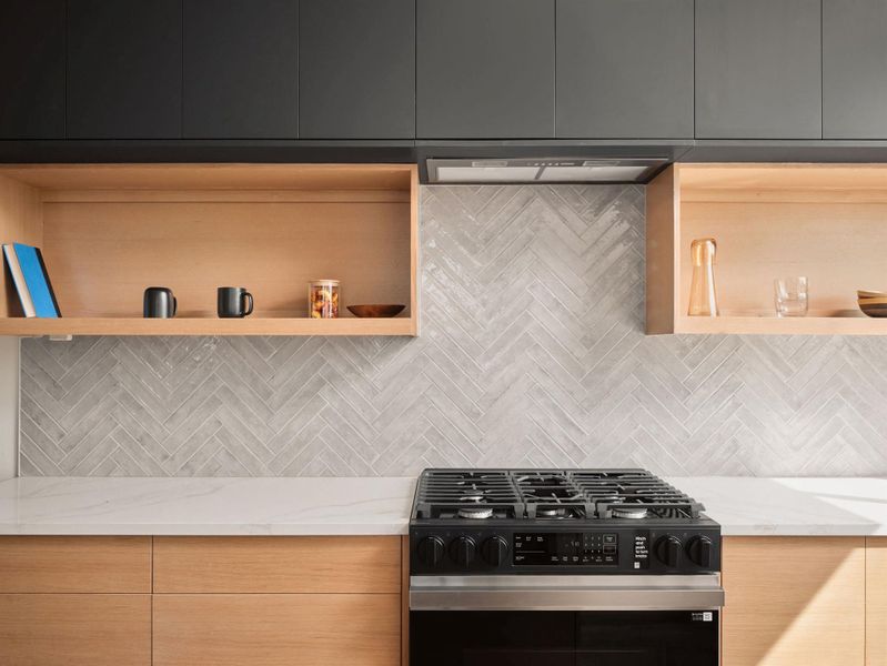 Kitchen featuring modern cabinets, tasteful backsplash, gas stove, and light stone countertops