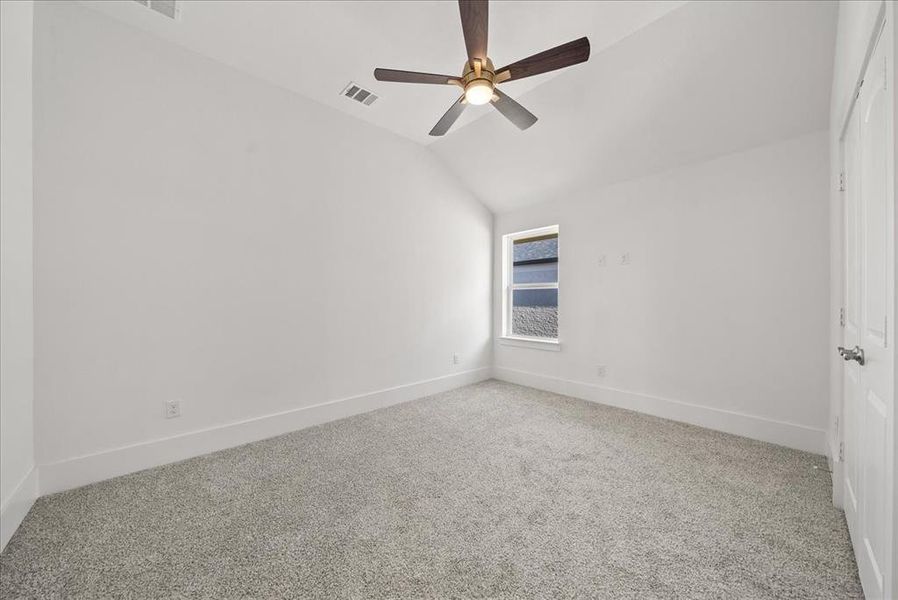Carpeted bedroom featuring lofted ceiling and a ceiling fan Carpeted bedroom featuring lofted ceiling and a ceiling fan