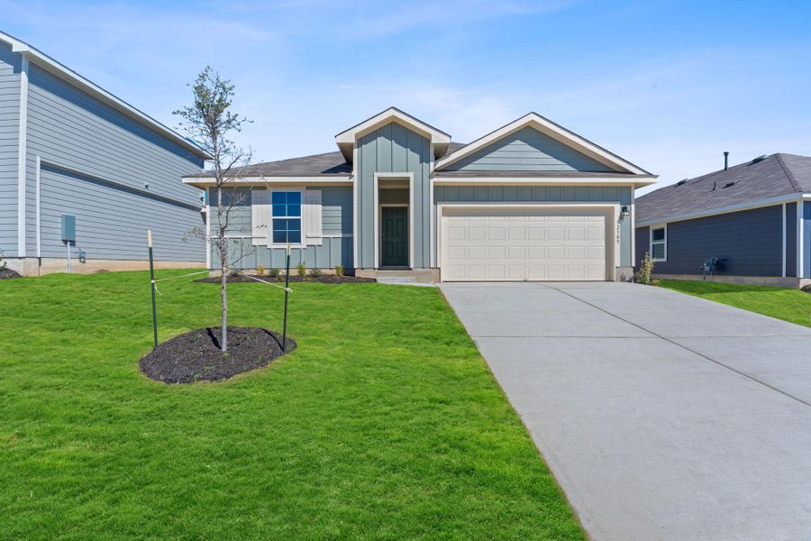 View of front of home with board and batten siding, concrete driveway, a front lawn, and an attached garage