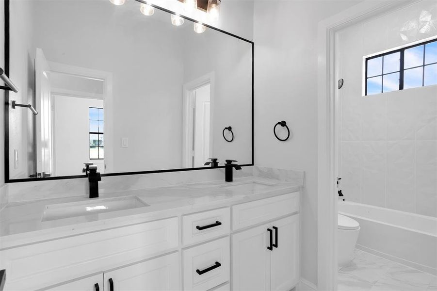 Full bathroom featuring dual vanity, toilet, tile patterned floors, and tiled shower / bath