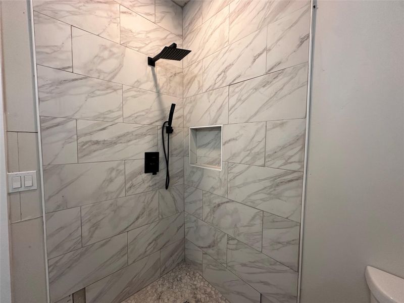 Full bath featuring tiled shower and toilet