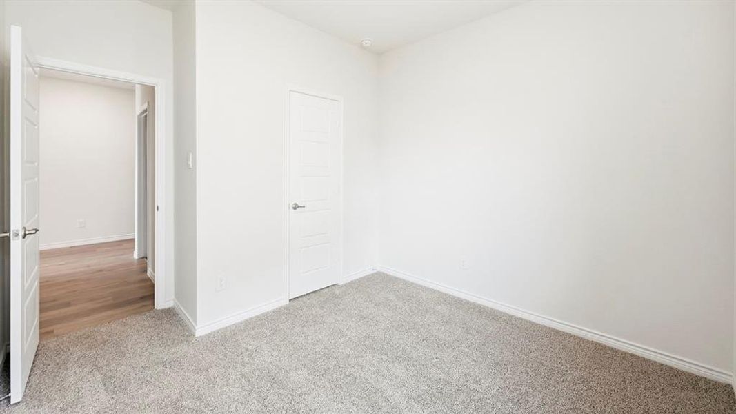 Unfurnished bedroom featuring light carpet and baseboards