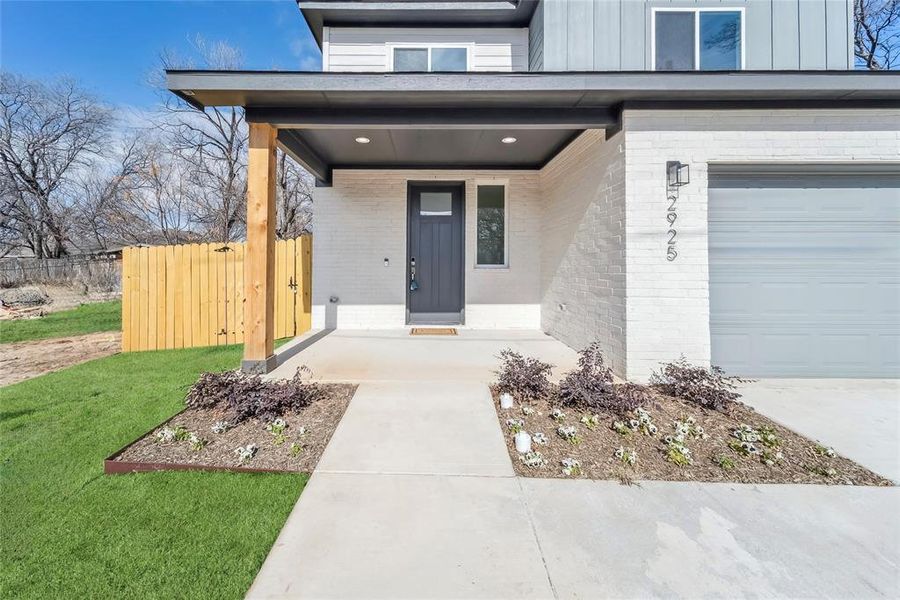 Front Entryway to property featuring a porch, a garage, and a lawn