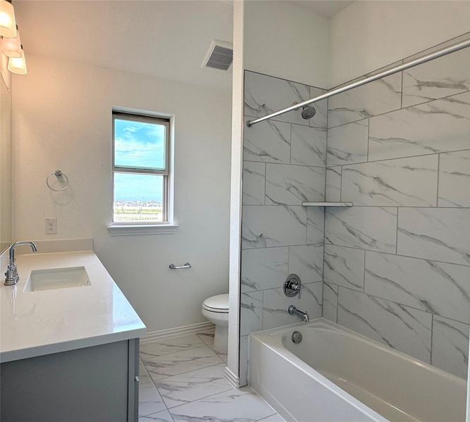 Full bathroom featuring marble look tile flooring, vanity, and bathtub / shower combination Full bathroom featuring marble look tile flooring, vanity, and bathtub / shower combination