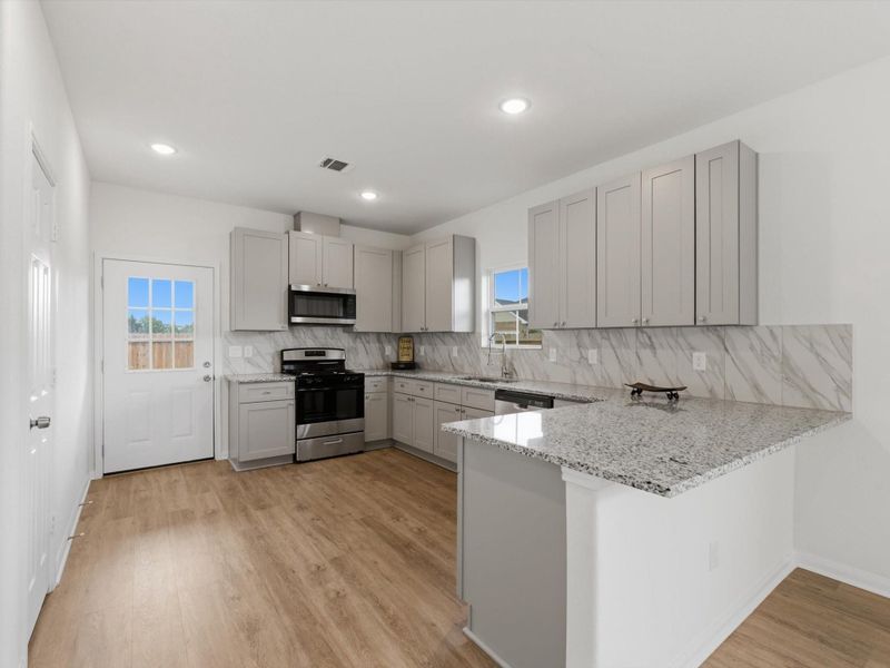 Designed with both style and functionality in mind, the kitchen features granite countertops, stainless steel appliances, soft-close cabinetry, and a spacious walk-in pantry.