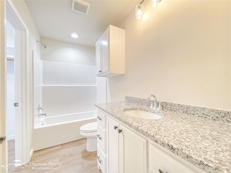 Bathroom featuring vanity, light wood finished floors, bathing tub / shower combination, and recessed lighting Bathroom featuring vanity, light wood finished floors, bathing tub / shower combination, and recessed lighting