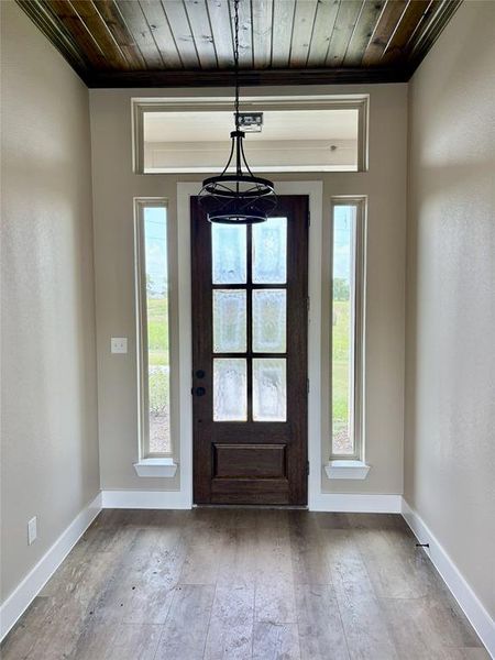 Foyer with wood ceiling, crown molding, hardwood / wood-style floors, and healthy amount of natural light Foyer with wood ceiling, crown molding, hardwood / wood-style floors, and healthy amount of natural light