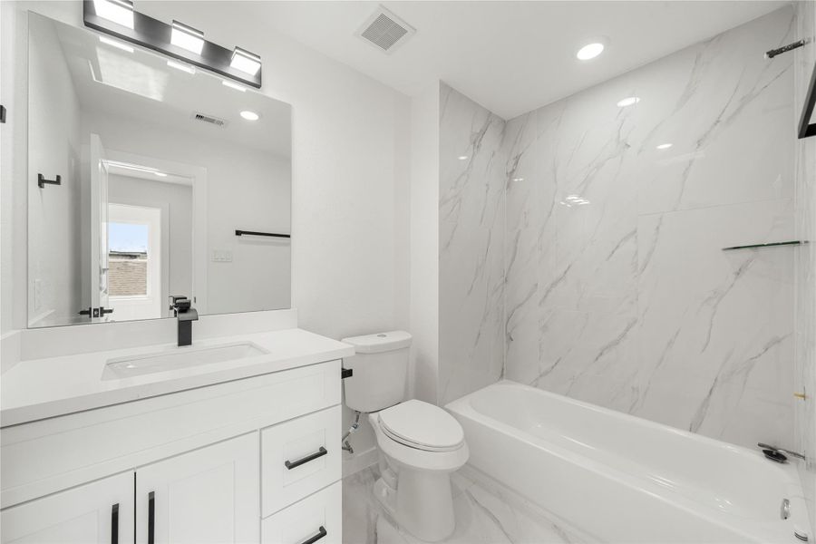 Secondary bathroom featuring a modern vanity with quartz countertop, sleek black fixtures, and a tub/shower combo with contemporary tile surround, offering a bright and functional design. Secondary bathroom featuring a modern vanity with quartz countertop, sleek black fixtures, and a tub/shower combo with contemporary tile surround, offering a bright and functional design.