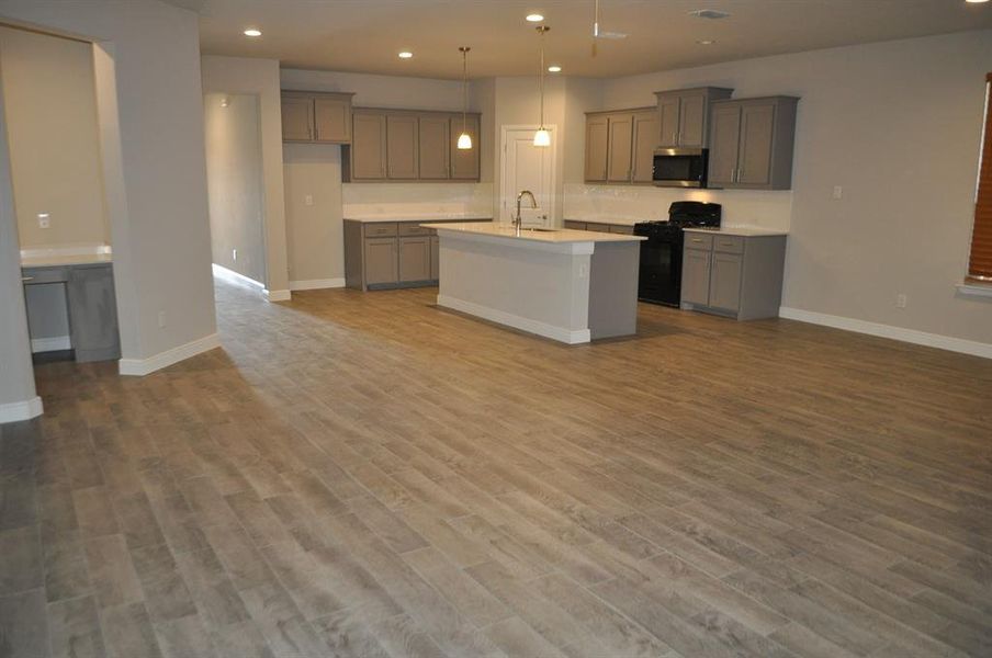 Kitchen with light hardwood / wood-style flooring, sink, a center island with sink, and black range with gas cooktop