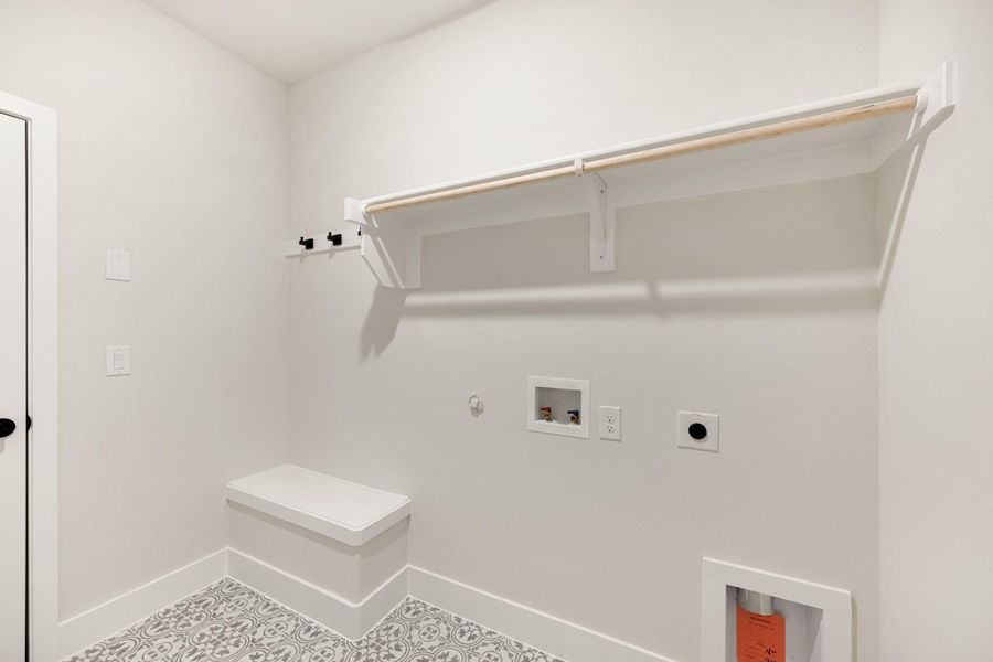 Laundry room with wall-mounted shelf, hanging rod, built-in bench, washer hookups, and patterned tile floor