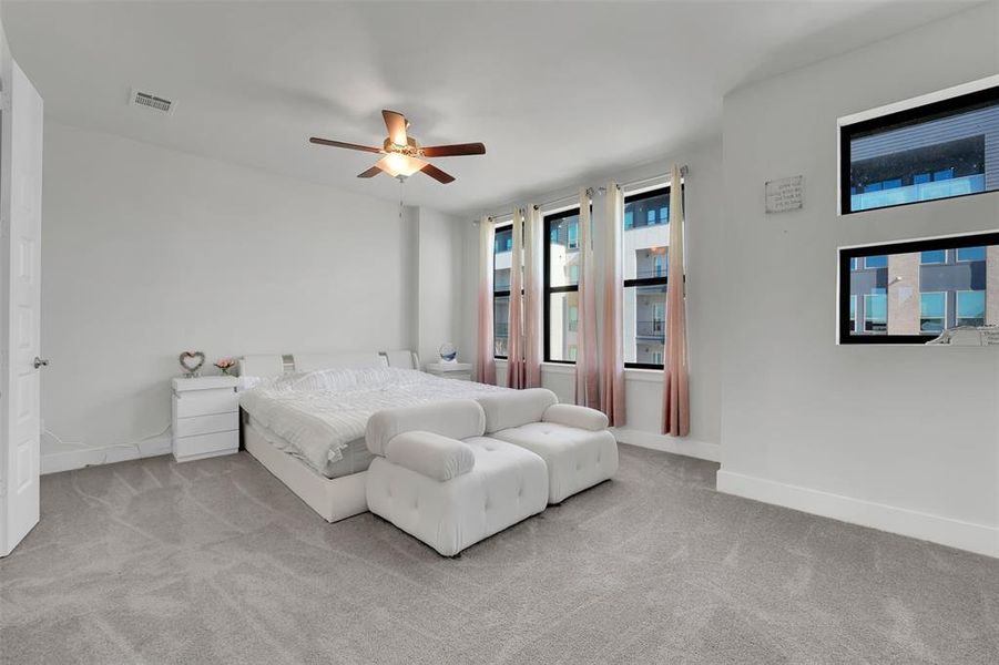 Carpeted bedroom featuring multiple windows and ceiling fan