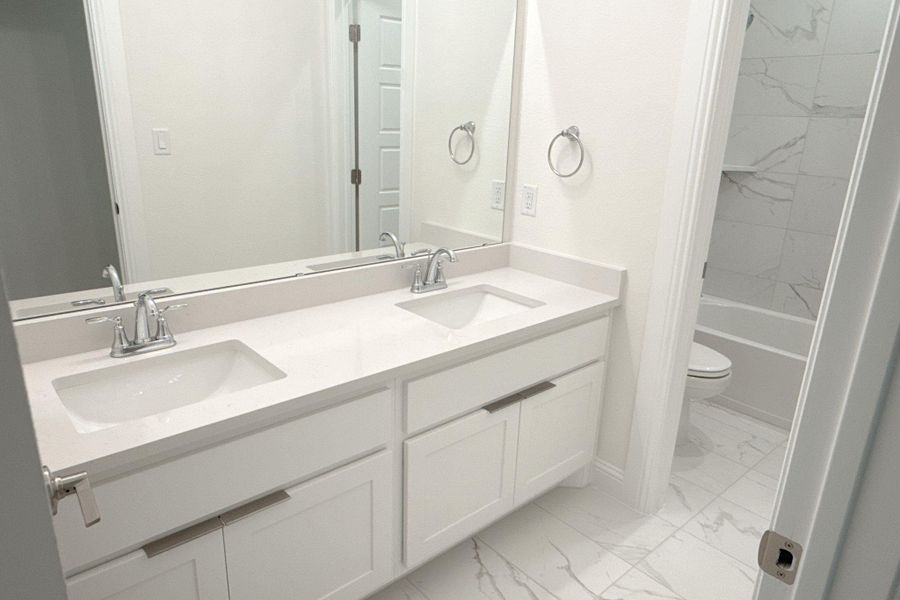 Full bath with double vanity, light marble finish flooring, and tub / shower combination