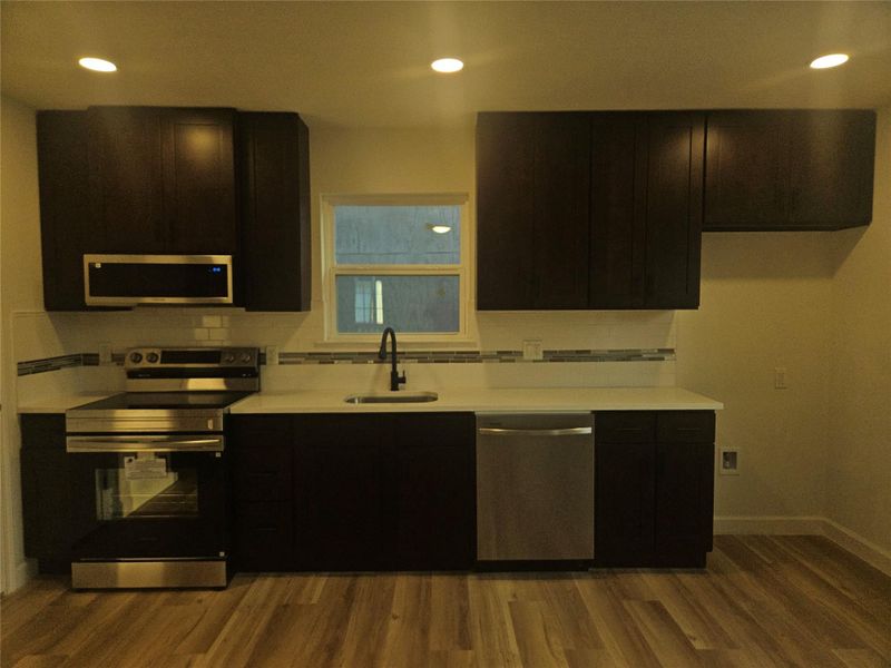 Kitchen with tasteful backsplash, wood finished floors, stainless steel appliances, and a sink