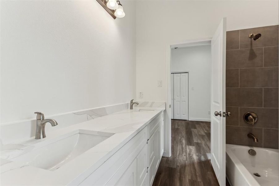 Bathroom featuring vanity, tiled shower / bath combo, and wood-type flooring