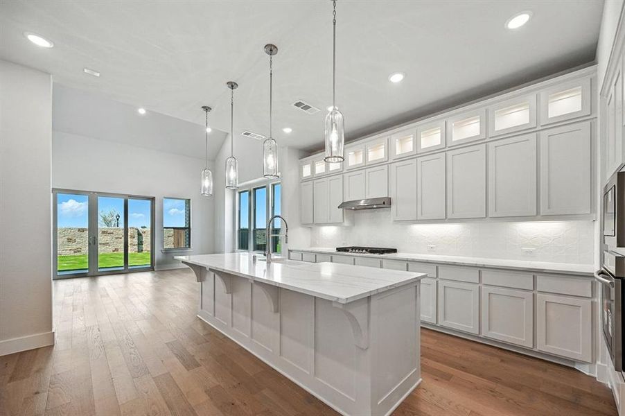 Kitchen featuring backsplash, white cabinetry, glass insert cabinets, recessed lighting, and a breakfast bar area Kitchen featuring backsplash, white cabinetry, glass insert cabinets, recessed lighting, and a breakfast bar area