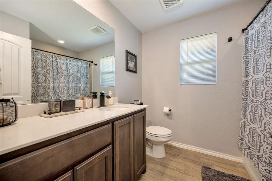 Full bath with curtained shower, vanity, and light wood-style floors