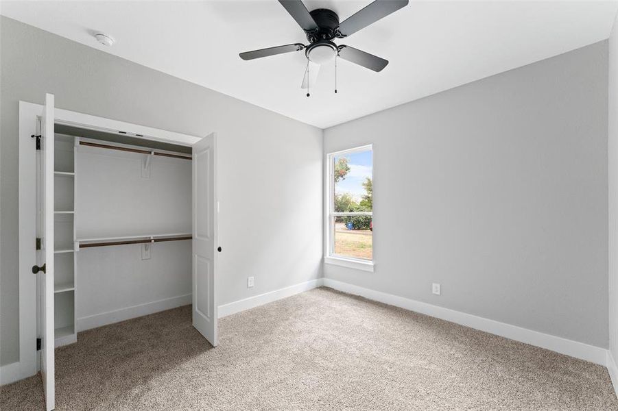 Unfurnished bedroom featuring light carpet, a closet, and ceiling fan
