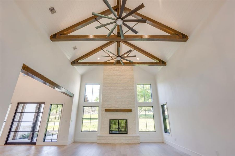 Unfurnished living room with a fireplace, light wood-style flooring, a ceiling fan, and healthy amount of natural light