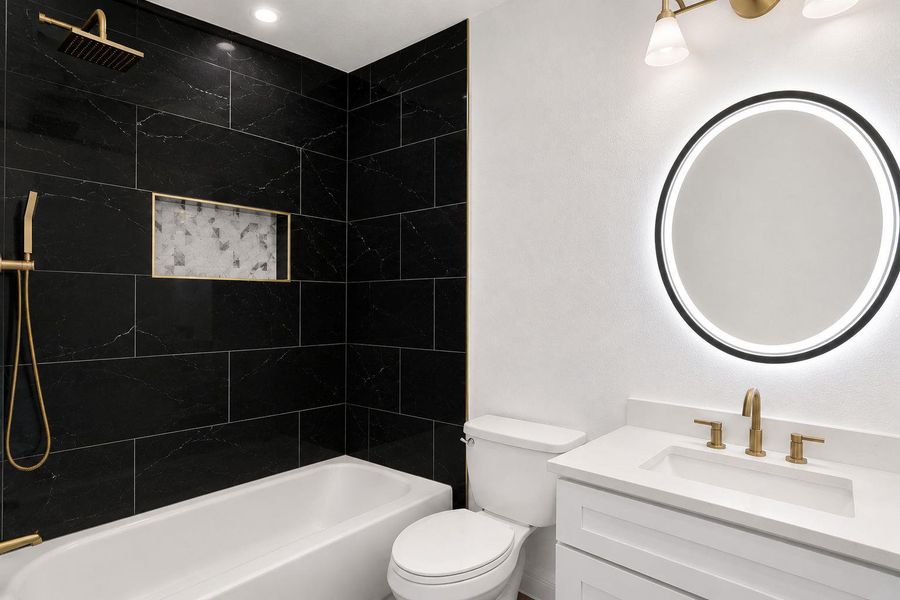 Indulge in a luxurious bathroom featuring striking dark tile work and refined gold fixtures.