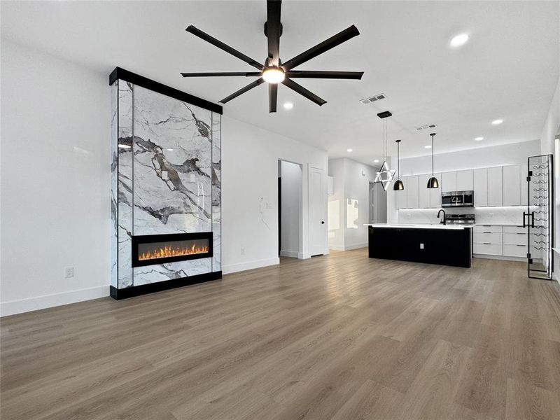Unfurnished living room featuring a premium fireplace, light wood-type flooring, ceiling fan, and recessed lighting
