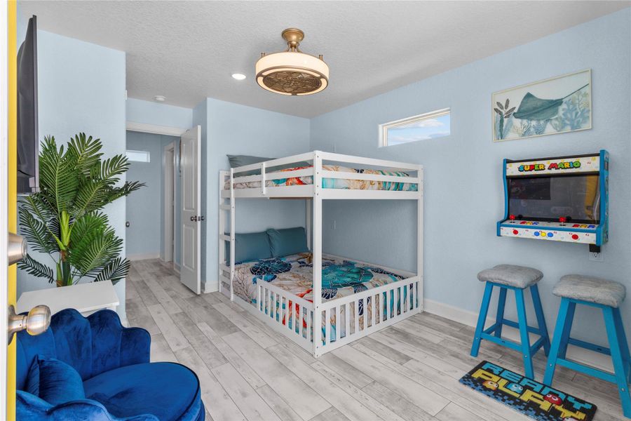 Video arcade game, TV and bunk beds.