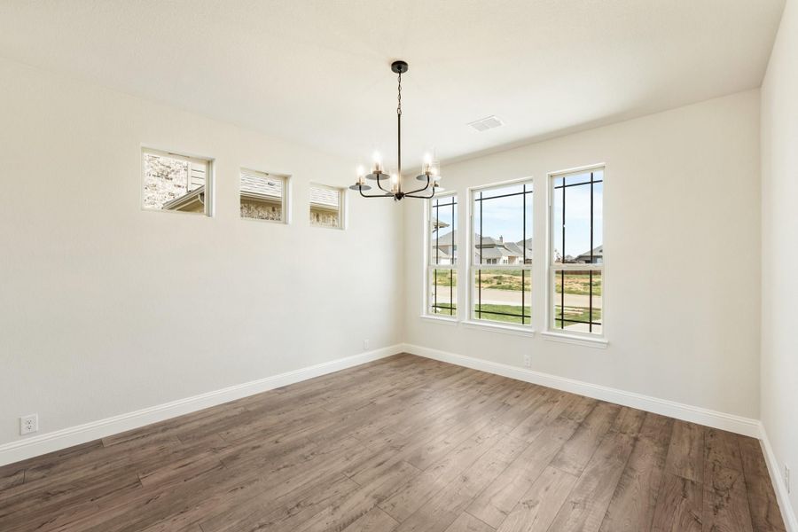 Empty dining room with hardwood floors, black chandelier, and large windows with neighborhood view