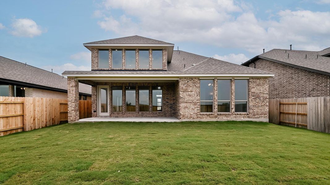 Rear view of house featuring a patio area, brick siding, and roof with shingles