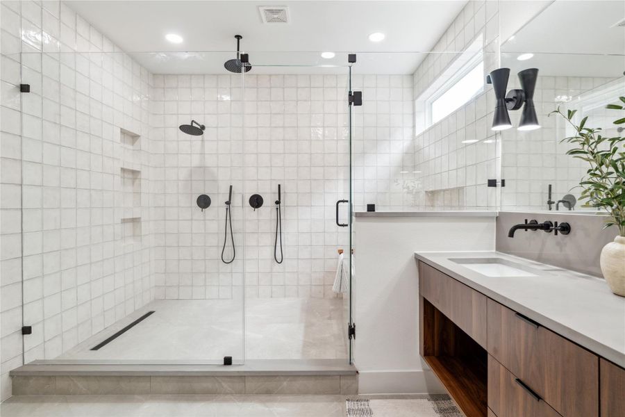 This oversized walk-in shower delivers a spa-worthy experience with dual rain heads, hand showers, and built-in niches—all enclosed in seamless glass to let the custom tile shine. This oversized walk-in shower delivers a spa-worthy experience with dual rain heads, hand showers, and built-in niches—all enclosed in seamless glass to let the custom tile shine.