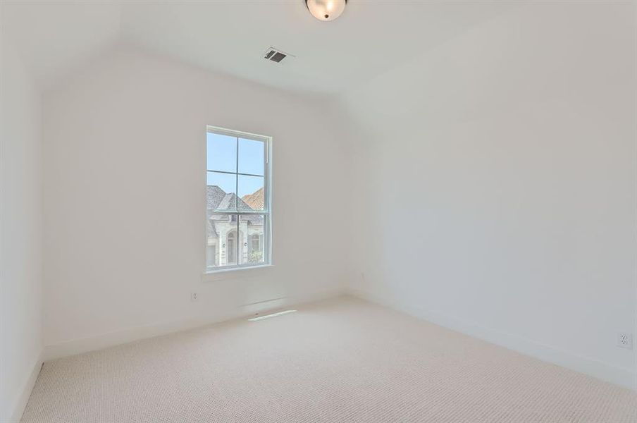 Carpeted empty room featuring vaulted ceiling