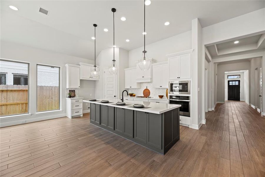 Amazing island kitchen offers Quartz countertops, white cabinetry, stainless steel appliances, gas cooktop, pendant lighting and a corner pantry.