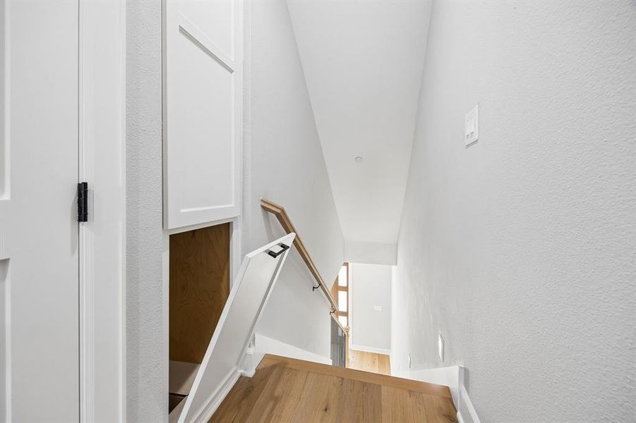 Stairway featuring a textured wall and wood finished floors Stairway featuring a textured wall and wood finished floors