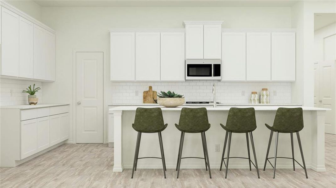 Kitchen with white cabinets, light hardwood / wood-style floors, and a kitchen island with sink