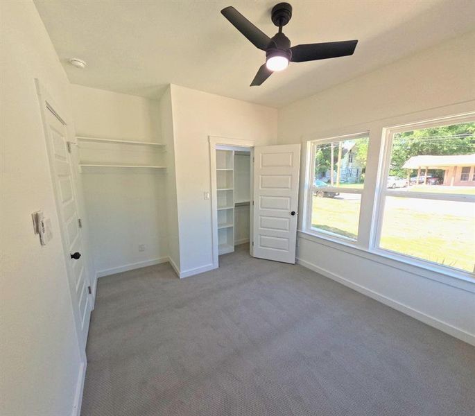 Unfurnished bedroom with dark colored carpet, ceiling fan, and a closet Unfurnished bedroom with dark colored carpet, ceiling fan, and a closet