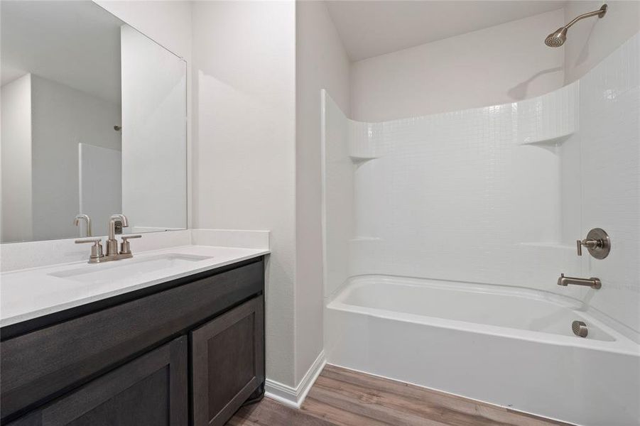 Full bathroom featuring wood finished floors, vanity, and shower / tub combination