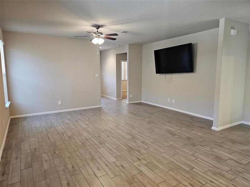 Living area featuring wood looking tile floors, ceiling fan and moldings.
