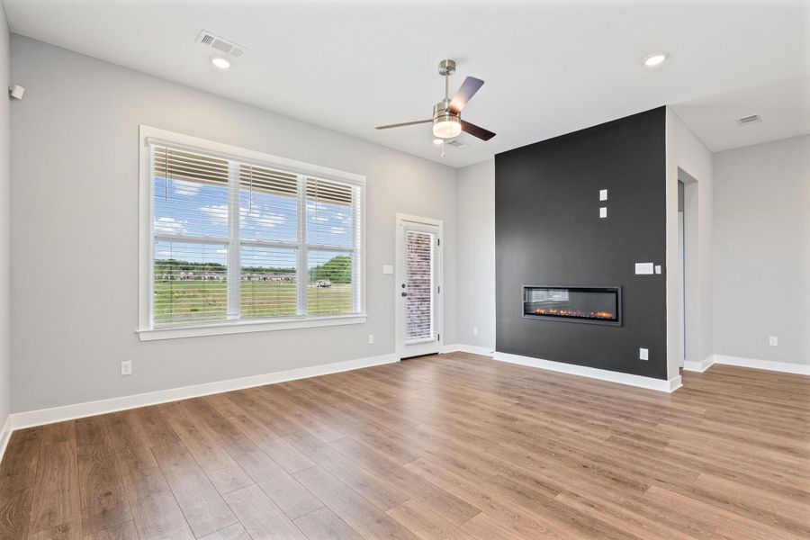 Unfurnished living room with a ceiling fan, a large fireplace, light wood-style floors, and recessed lighting