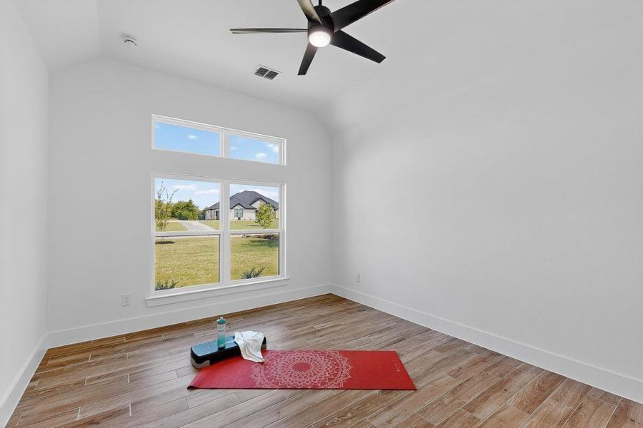Exercise area with wood finished floors, a ceiling fan, and lofted ceiling