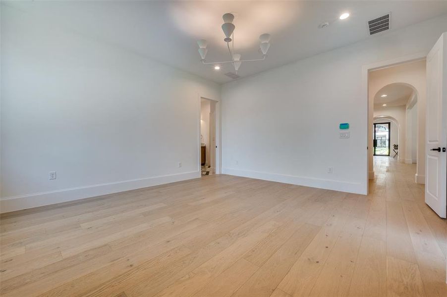 Spare room featuring arched walkways, light wood finished floors, a chandelier, and recessed lighting