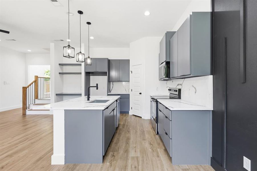 Modern kitchen featuring light gray cabinetry, white countertops with veining, and wood-finish flooring Modern kitchen featuring light gray cabinetry, white countertops with veining, and wood-finish flooring