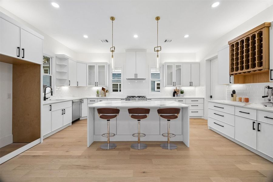 The kitchen was designed to balance functionality with a clean contemporary aesthetic, featuring extensive cabinetry, oversized prep surfaces, designer lighting, and an open layout that remains connected to the surrounding living spaces. Positioned at the center of the home, the space was thoughtfully arranged for entertaining, daily use, and long-term flexibility without sacrificing visual openness. (digitally staged)