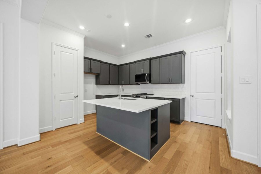 The heart of the home. Anchored by an island with a sink and ample pantry storage, this kitchen is where memories are made.