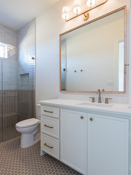 Another secondary bathroom with painted cabinets and earth tone tile floors and shower.