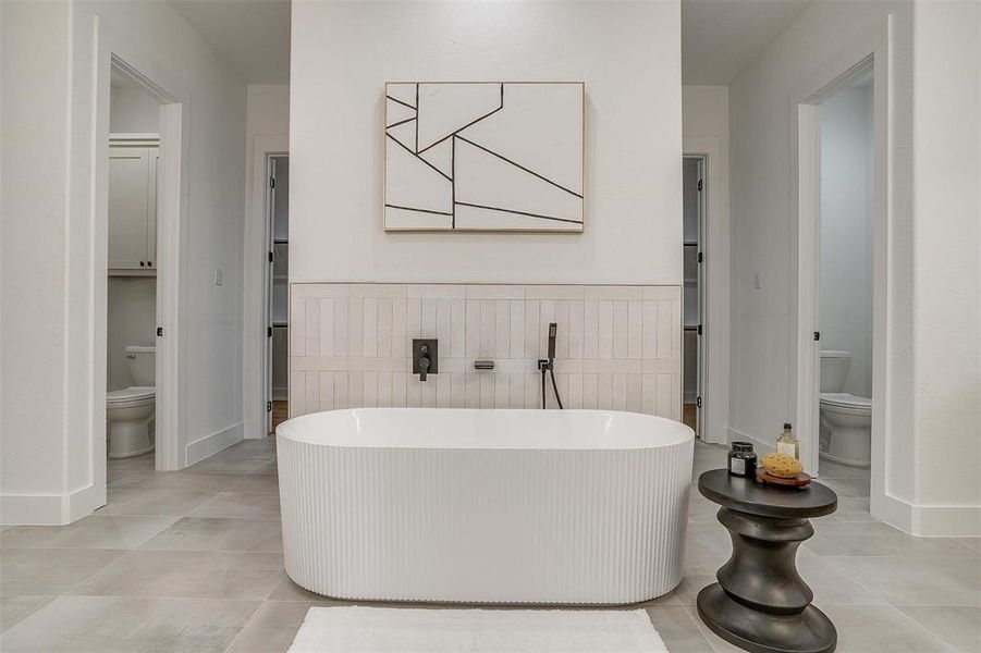 Bathroom with toilet, a tub to relax in, and tile patterned floors