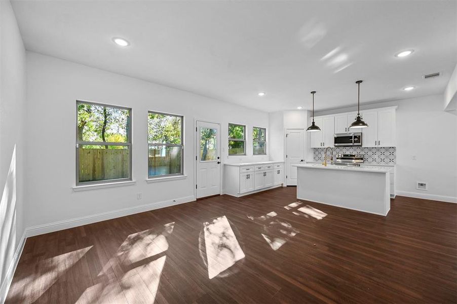 Kitchen with white cabinets, dark hardwood / wood-style flooring, stainless steel appliances, and a healthy amount of sunlight