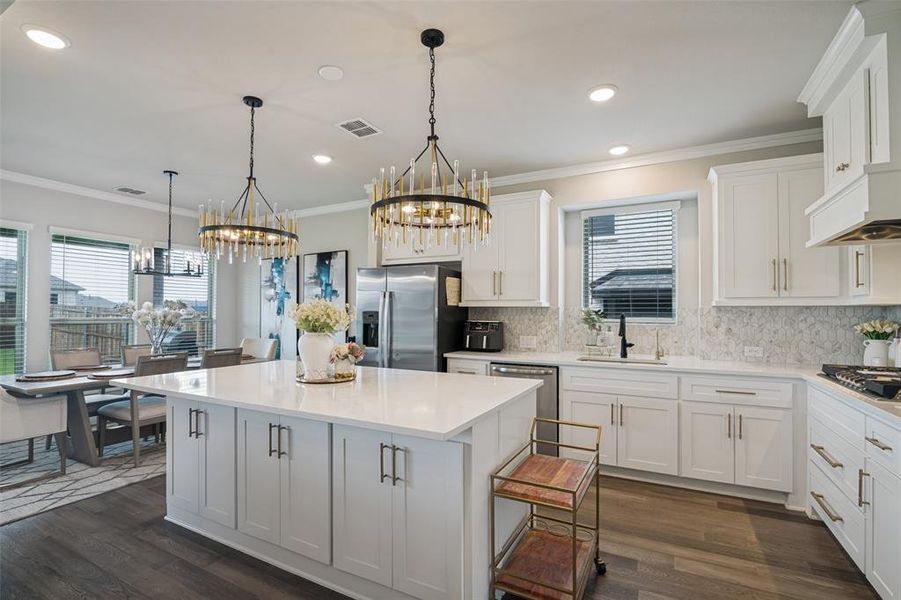 Open-concept kitchen with a large central island, white shaker cabinetry, quartz countertops, and wood-finish flooring