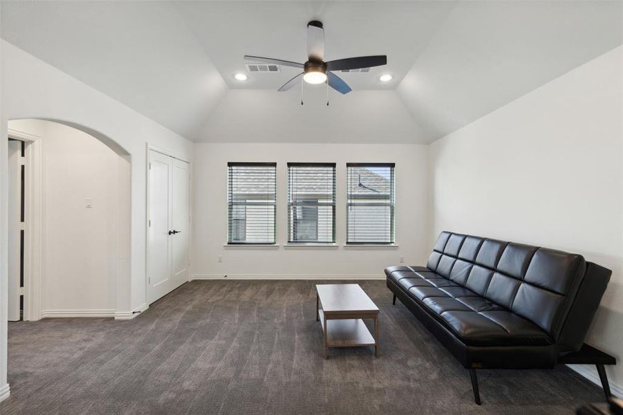 Sitting room with ceiling fan, vaulted ceiling, and dark carpet