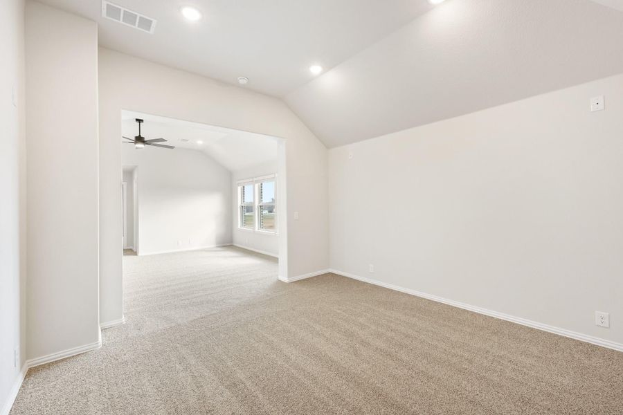 Empty room with vaulted ceiling, beige carpet, and arched doorway leading to second room with ceiling fan Empty room with vaulted ceiling, beige carpet, and arched doorway leading to second room with ceiling fan