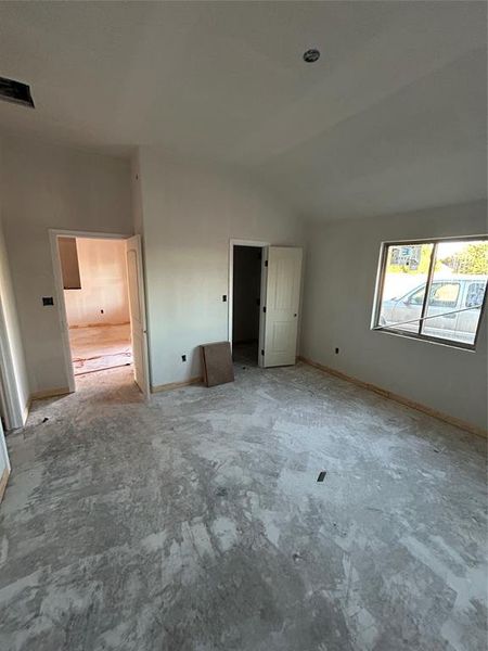 Unfurnished bedroom with baseboards and lofted ceiling