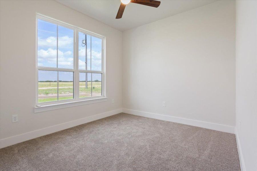 A quiet bedroom offers serene outdoor views through its large windows and comfort underfoot with plush carpeting.